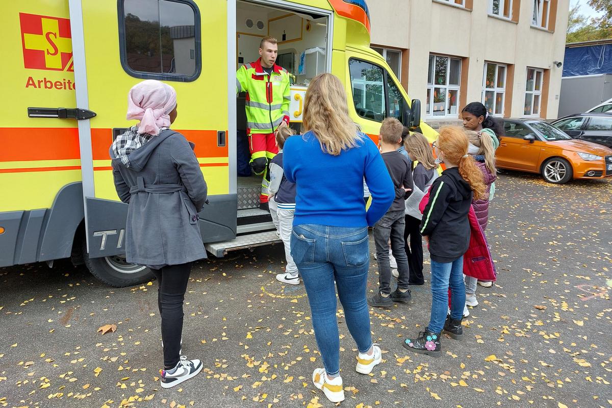ASB-Mitarbeiter steht in der Tür eines Rettungswagens und erklärt den Schülerinnen und Schülern, dessen Ausrüstung und Einsatzbereiche. 