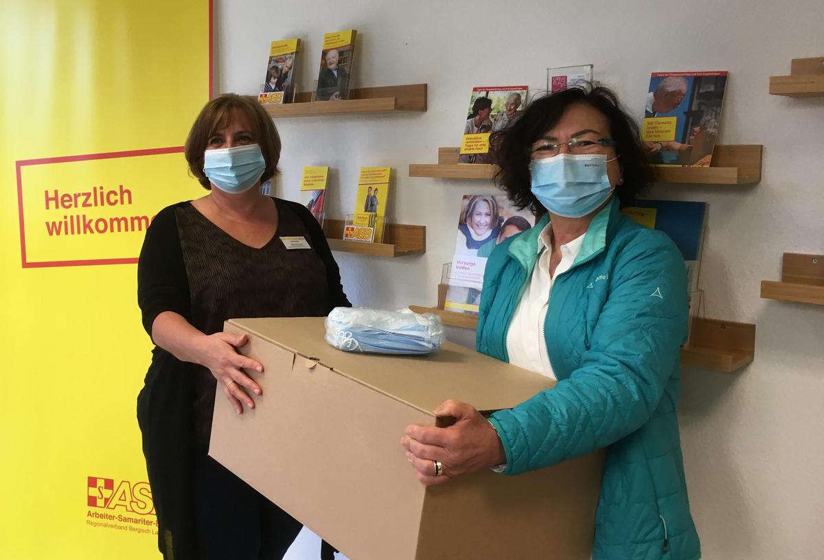 Irina Herz von der ASB-Begegnungsstätte in Leverkusen (l.) nimmt von Karin Priem von der Firma Yanfeng die Spende von 3000 Masken entgegen (Foto: ASB Bergisch Land).
